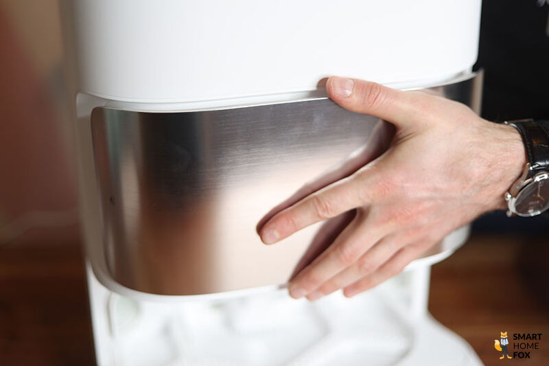 Die silberne, magnetische Klappe der Dreame L10s Ultra Basisstation wird abgenommen.